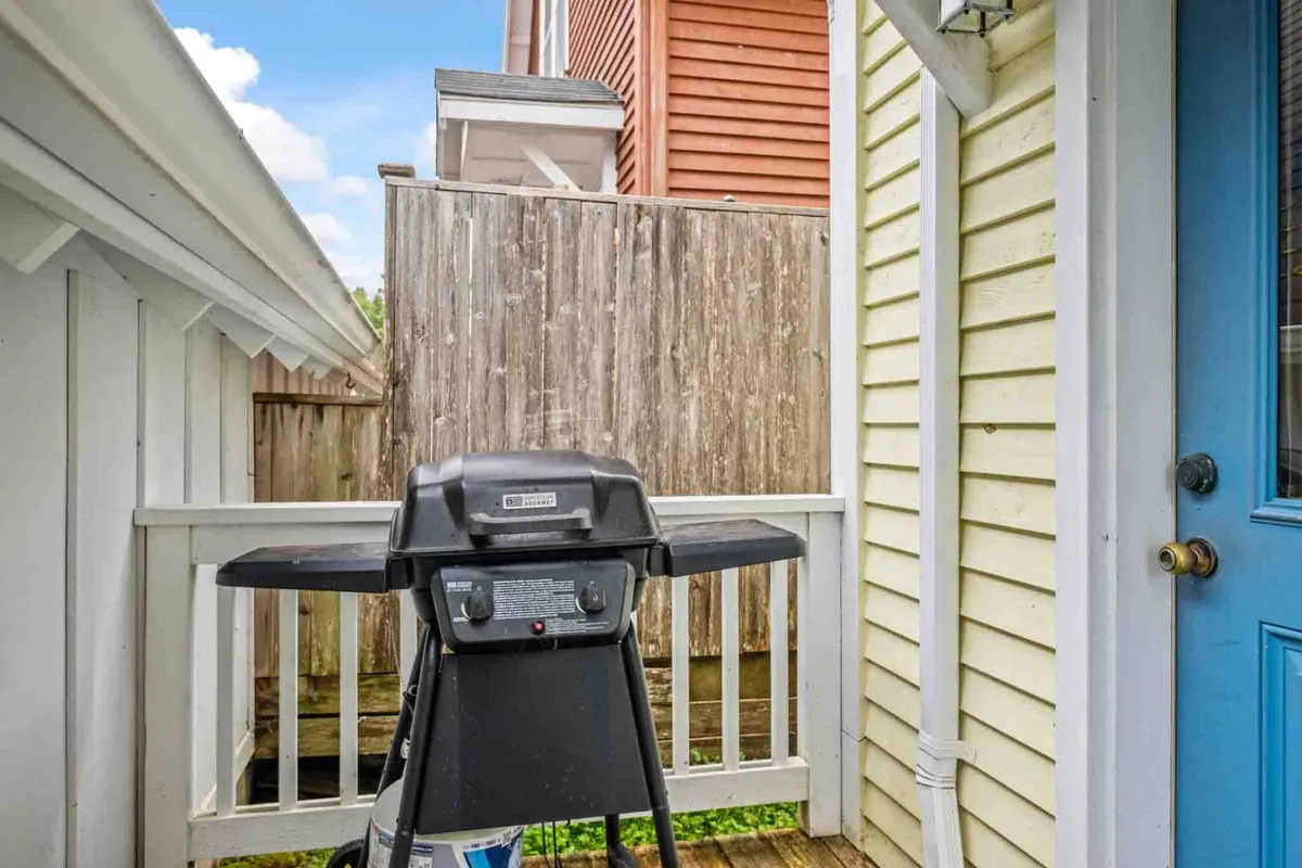 An inviting exterior shot showcasing a blue door, a fence, and a grill set on a patio. The setup suggests a casual space for outdoor dining and social gatherings, enhancing the sense of shared experiences and evening relaxation.